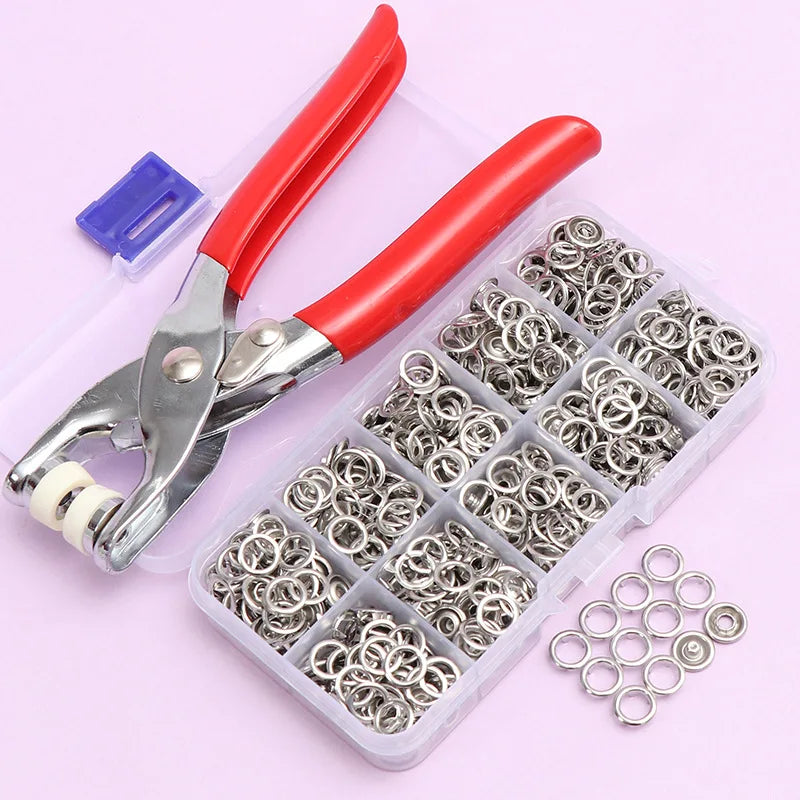 A pair of red-handled pliers is shown next to a clear plastic container filled with metal and plastic snap buttons.