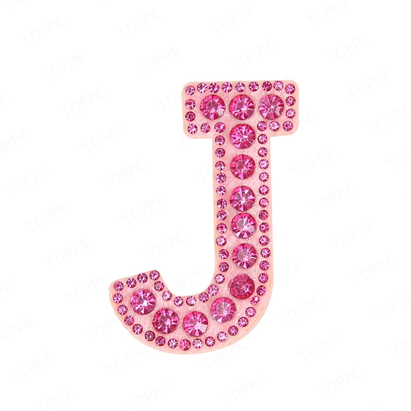 A pink rhinestone letter J patch used for DIY projects.