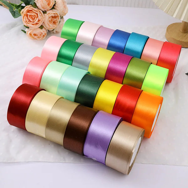 A collection of colorful satin ribbon rolls in various shades are displayed on a white surface.