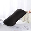 A black microbead neck pillow resting on a white surface next to a woven basket and some paper.