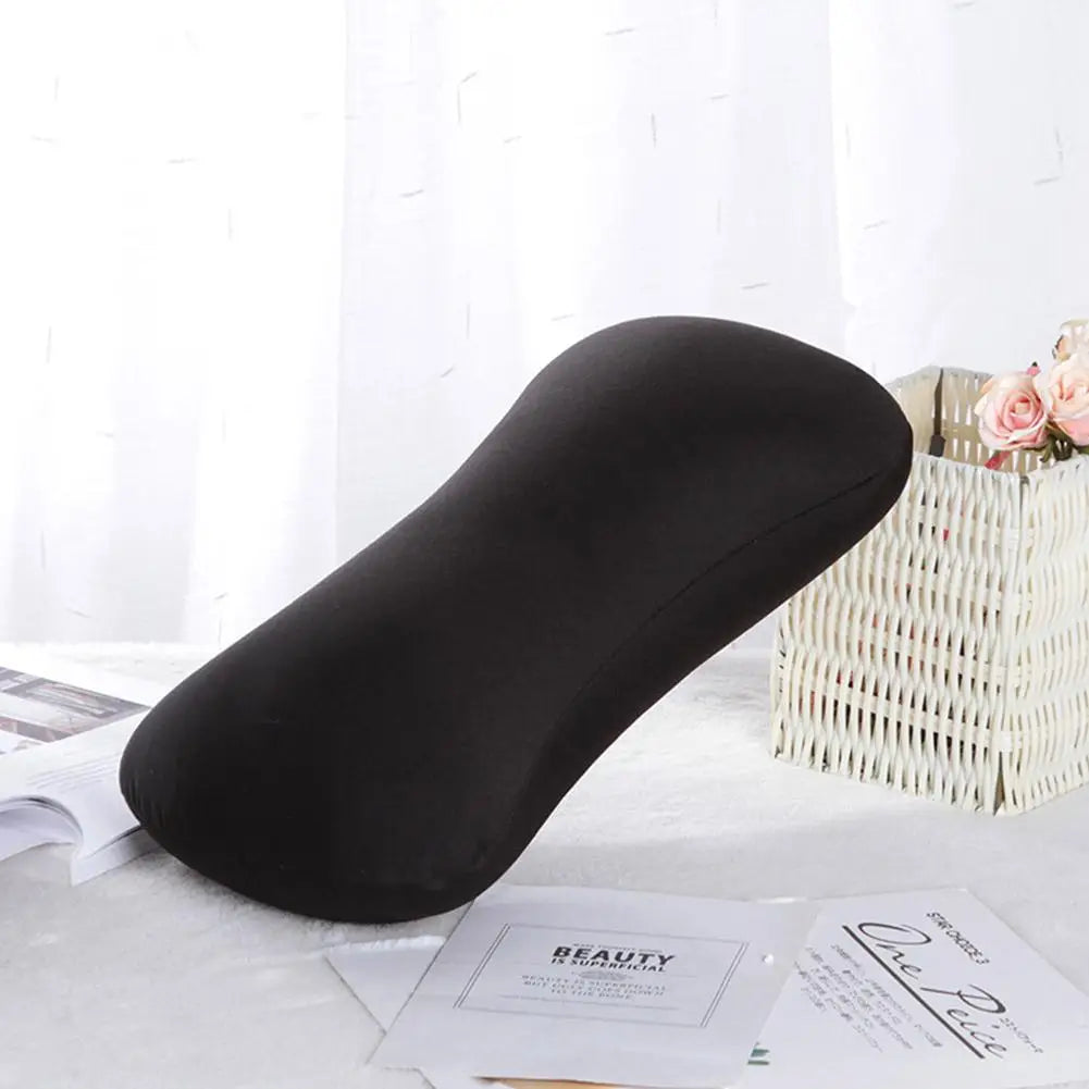 A black microbead neck pillow resting on a white surface next to a woven basket and some paper.