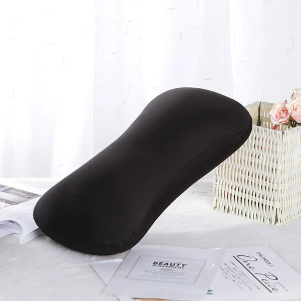A black microbead neck pillow resting on a white surface next to a woven basket and some paper.