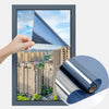 Hand holding a sheet of reflective mirror window film being applied to a window frame.