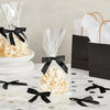 A display of white popcorn in clear bags tied with black satin ribbon bows on a marble surface.