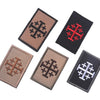 Four embroidered patches featuring a cross design in brown, black, red, and silver thread.