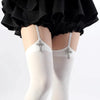 Pair of white suspender socks with silver cross details worn under a black ruffled skirt.
