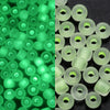 A close-up view of green glow-in-the-dark glass seed beads, some translucent and others opaque.