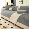 A light gray sherpa anti-slip sofa cover with cream accents and pillows displayed on a modern sofa.