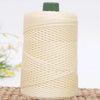A spool of cream-colored crochet ice rope with a green cap resting on a woven mat.