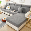 A gray leaf pattern sofa slipcover displayed on a white modern sofa with light wood flooring.