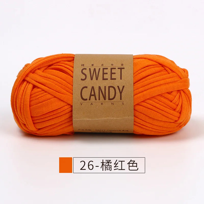 A skein of bright orange hand-dyed yarn labeled Sweet Candy Yarns for crochet and knitting.