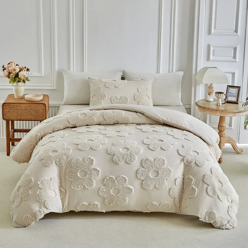 A cream tufted floral duvet cover set with matching pillowcases displayed on a bed against a white wall.