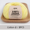 A ball of yellow 100% organic cotton yarn is displayed on a wooden board.