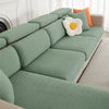 A light sage green jacquard elastic sofa cushion slipcover with a textured weave and an orange accent pillow.