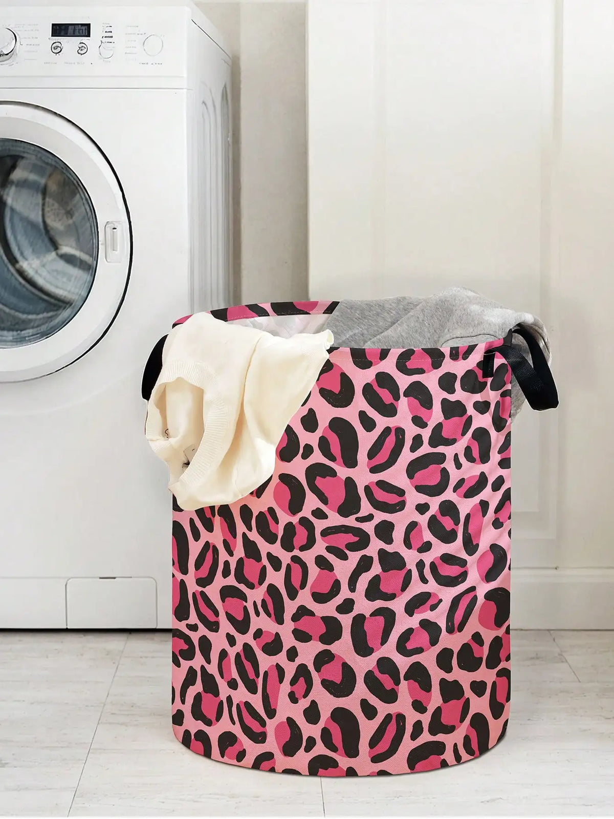 A pink leopard print foldable laundry basket next to a white washing machine.
