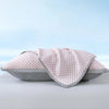 A pink quilted summer cooling bean pillow cover resting on a white surface.