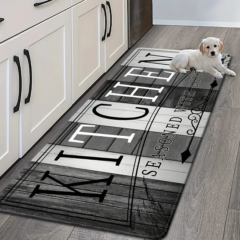 A long, rectangular kitchen mat with a distressed black and white design is placed on a wooden floor.