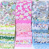 A stack of floral cotton fabric in various pink, green, and blue patterns for quilting and crafting.