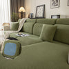 A moss green plush elastic sofa cushion cover displayed on a modern sofa with neutral decor.