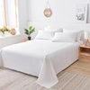 White premium flat bed sheet spread on a bed with natural wood accents and a light gray rug.