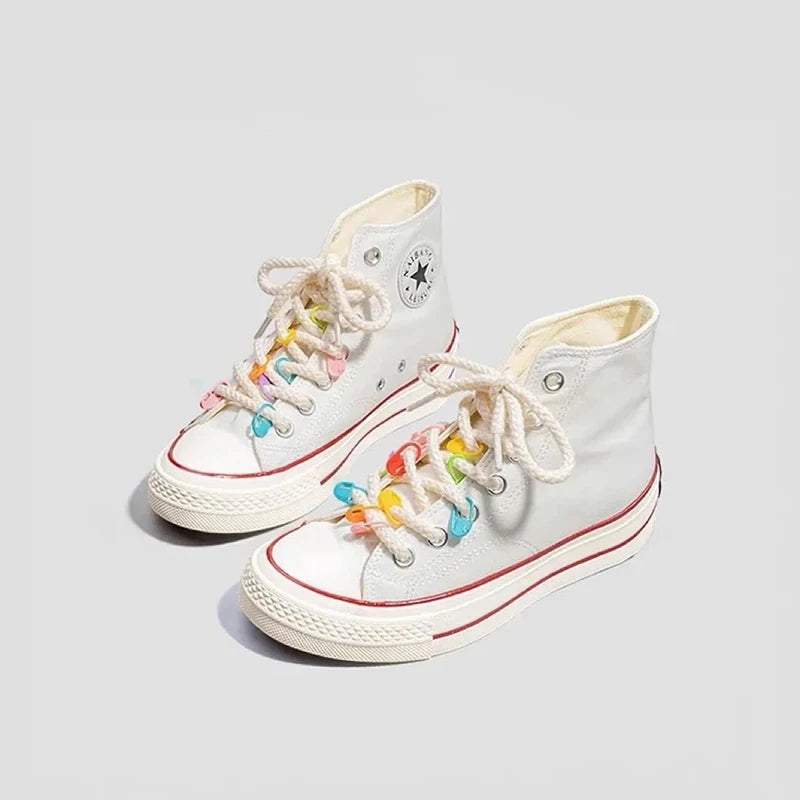 A pair of white canvas stitch markers with colorful embroidery and laces.