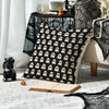 A set of four Halloween cushion covers featuring ghost, pumpkin, and skull designs displayed on a gray rug.