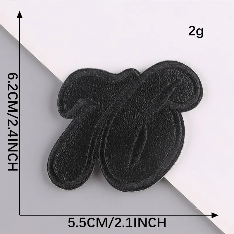 A set of five black embroidered leather patches with self-adhesive backing shown against a white background.