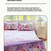 A purple and pink floral print bed skirt set displayed on a bed with pillows and a bedside table.