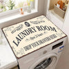 A laundry room featuring a white washing machine with a decorative label on the door and a window view.