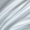 A close-up of a silky, light blue fabric draped and flowing softly.