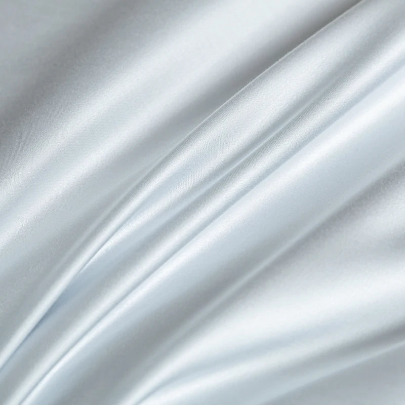 A close-up of a silky, light blue fabric draped and flowing softly.
