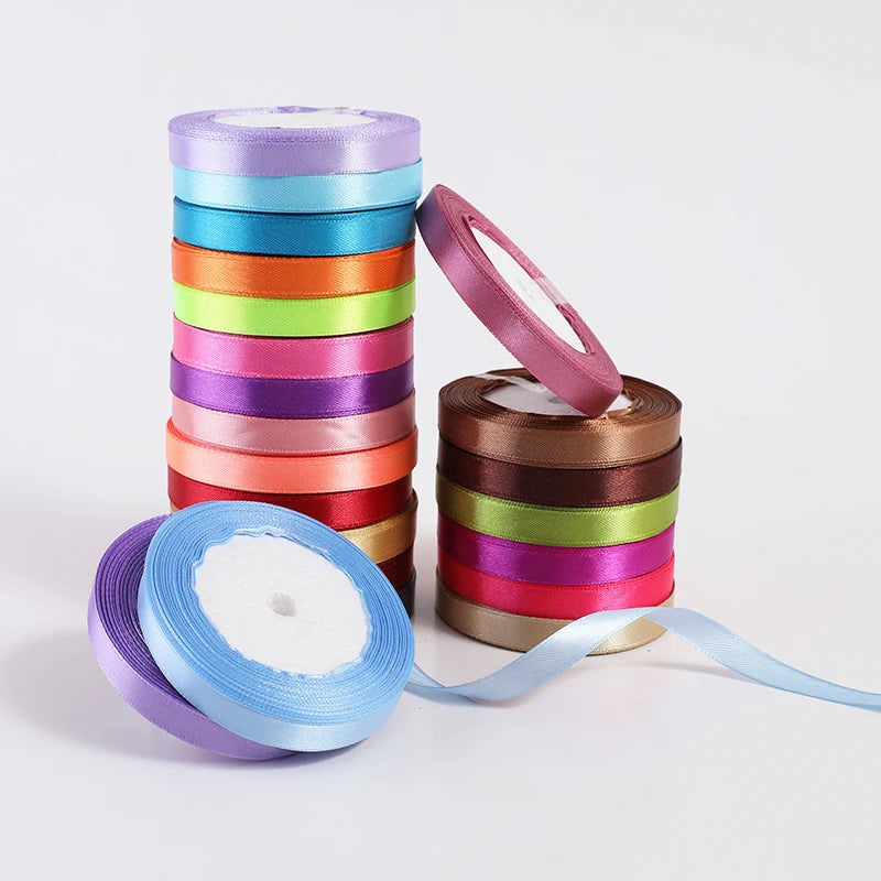 A stack of satin ribbon rolls in assorted colors, including purple, blue, green, pink, and orange.