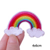 A hand holds a white felt rainbow cloud iron-on patch with a pink, red, orange, yellow, green, and blue gradient.