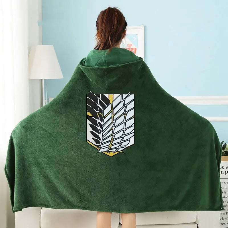 Dark green flannel cloak with a white and yellow leaf design displayed on a light blue wall.