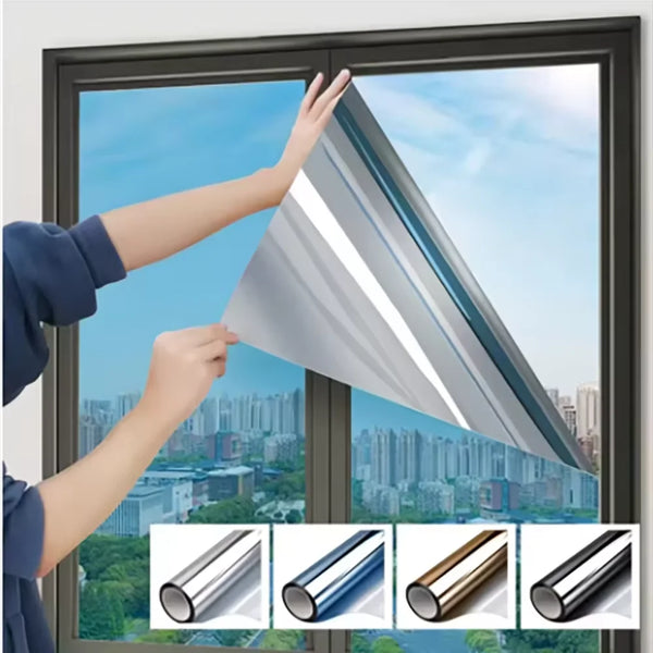 A hand is adjusting a silver insulated glass film on a window pane to provide privacy and sun protection.