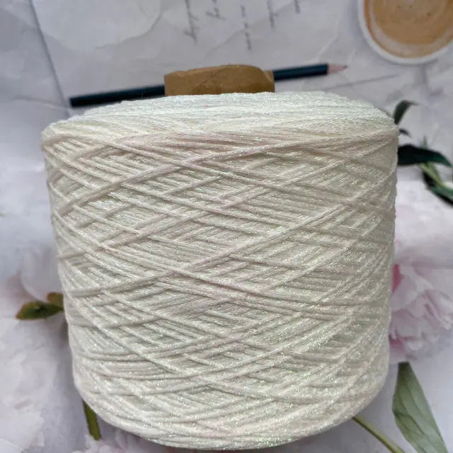 A spool of glitter metallic yarn for crochet and knitting is shown on a white surface.