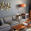 A gray sofa with a brown wooden coffee table and an orange lamp on a gray wall.