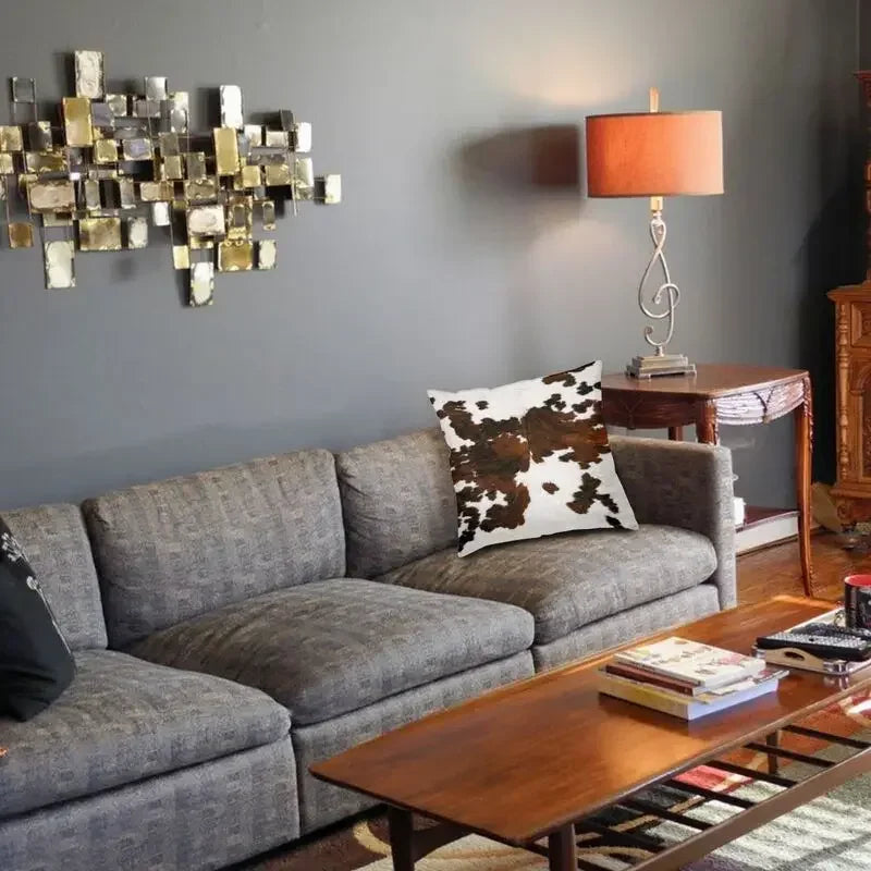 A gray sofa with a brown wooden coffee table and an orange lamp on a gray wall.