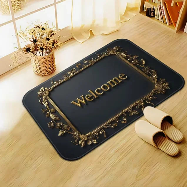 A dark entrance door mat with gold leaf detailing and the word Welcome placed on a light wooden floor.