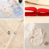A collection of fabric snaps, including various sizes and colors, alongside a red elastic band and a cream-colored garment wi