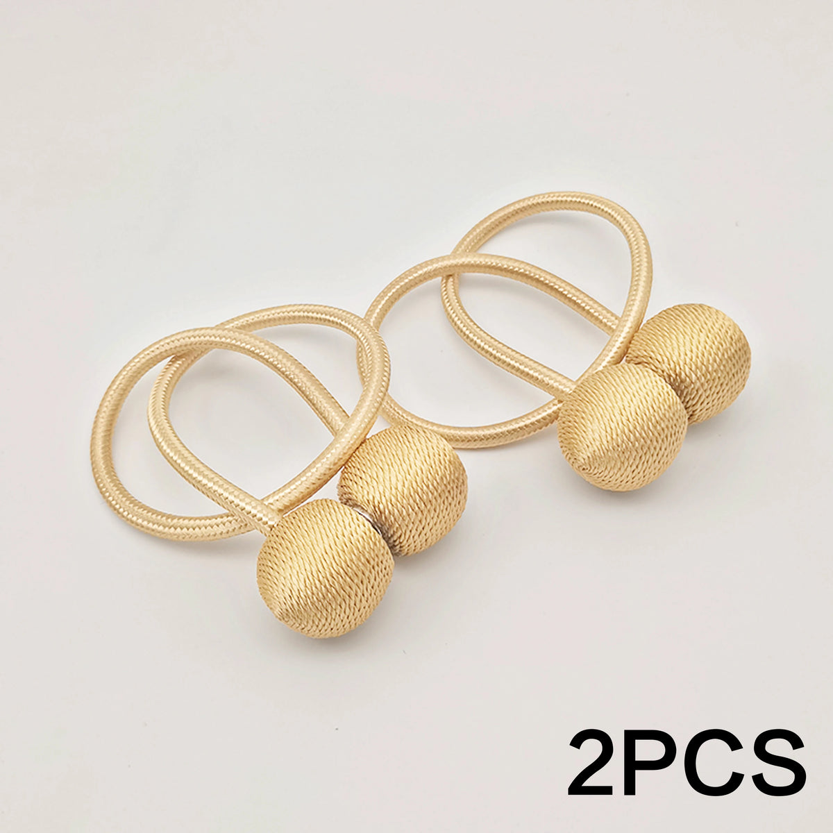 Two gold-colored minimalist magnetic ball curtain tiebacks on a white background.