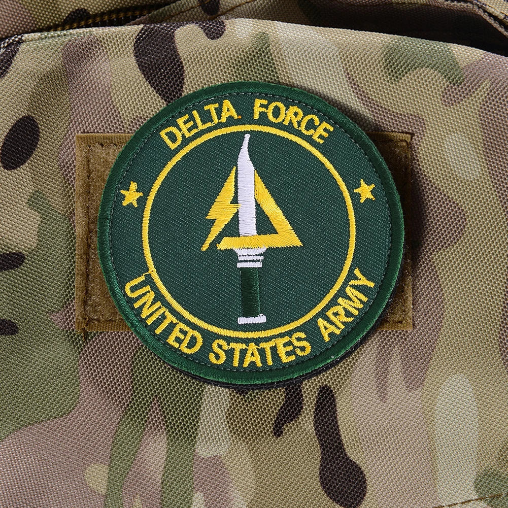 A dark green embroidery patch featuring a yellow delta symbol and text for the United States Army on a camouflage fabric.