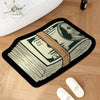A black non-slip rug features an illustration of a folded dollar bill with a portrait on it.