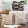 Three throw pillows in beige and gray diamond patterns displayed on a wooden surface.