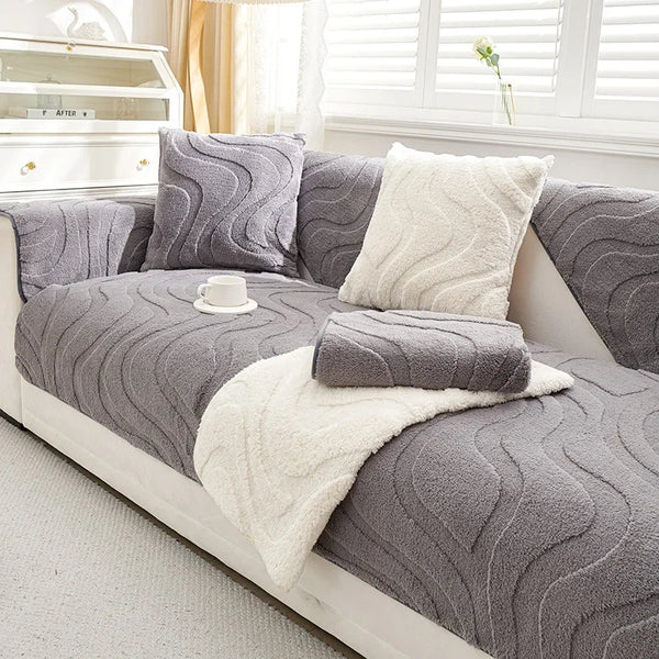 Gray textured sofa cushion cover with cream throw pillows and a white teacup on a light-colored sofa.