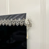 Black table runner featuring intricate silver embroidered mesh lace with a tassel detail.