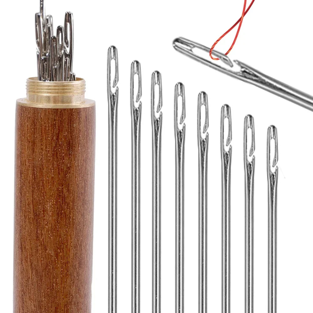 A set of multi-size hand sewing needles with a wooden storage tube and a red thread.