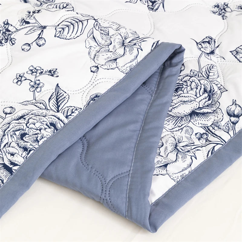 A close-up of a light blue floral summer duvet featuring detailed botanical illustrations on white fabric.