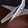 Silver professional pinking shears cutting into brown leather fabric
