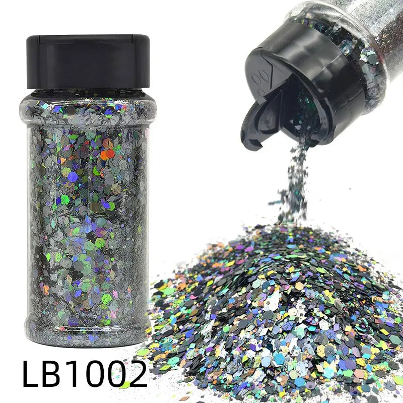A glass bottle of holographic craft nail glitter mix next to a pile of iridescent glitter powder.
